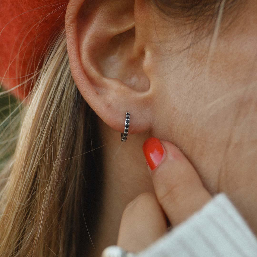 Woman wearing Sterling Silver huggie earrings with black crystals