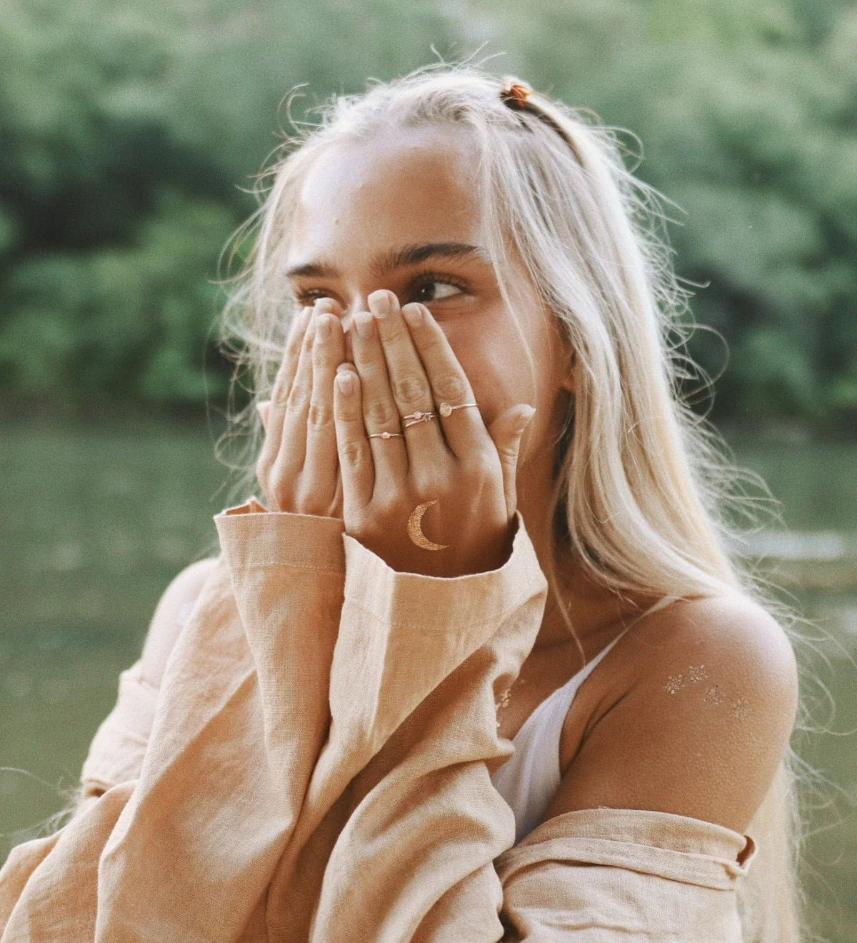 celestial jewellery with moon and star necklace, moonstone ring and gold star earrings styled on neutral stone background representing moon and star symbolism