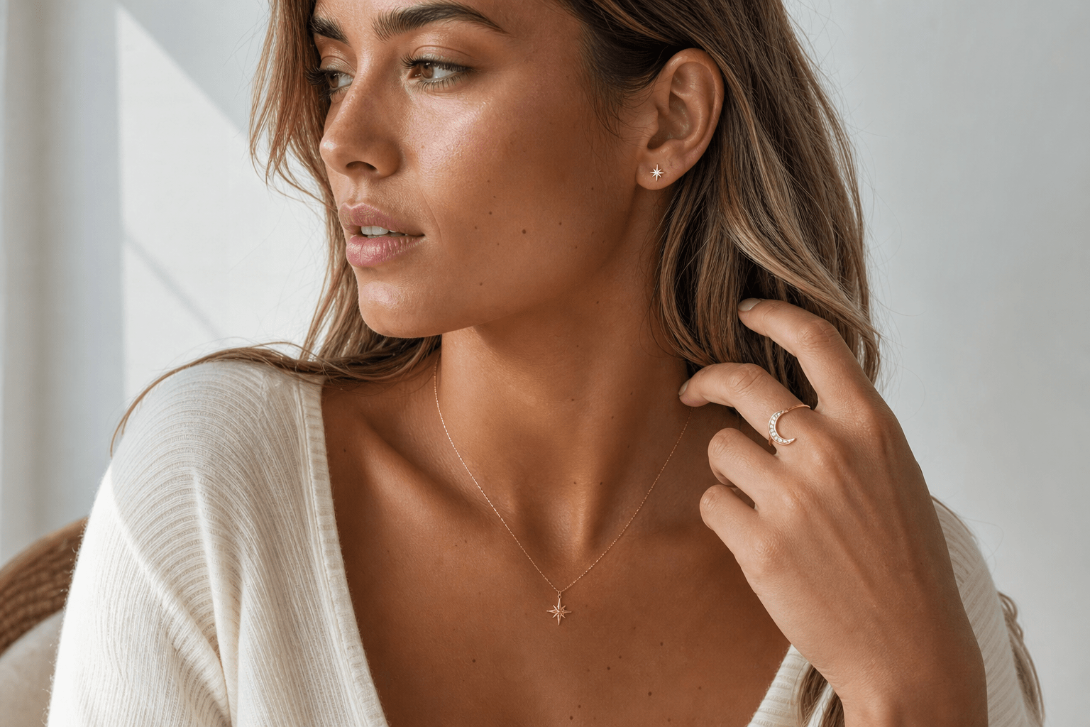 Young woman wearing delicate celestial jewellery including a star necklace, moon ring, and small earrings.