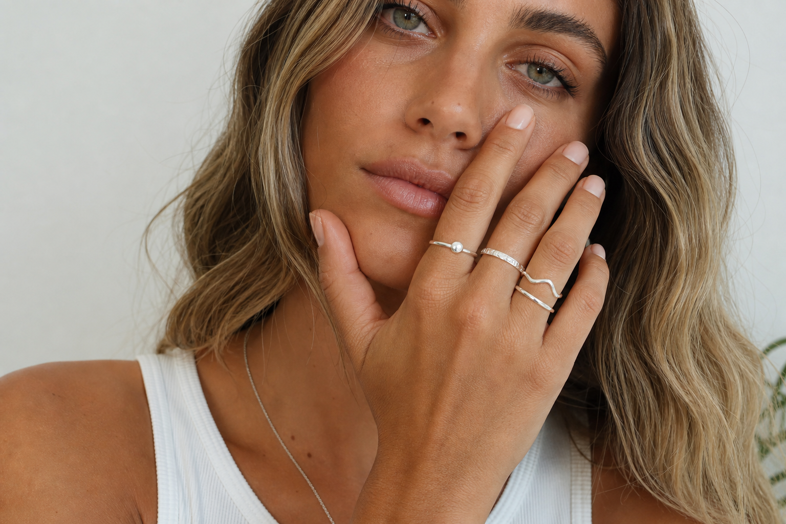 Young woman wearing multiple sterling silver rings on her hand in natural light