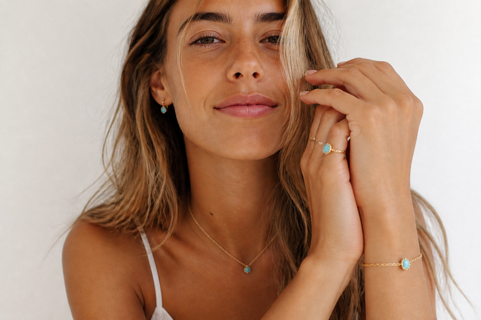 Young woman wearing delicate gold turquoise jewelry in natural light