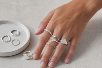 Several sterling silver rings in different styles including a plain band, stackable rings, a signet ring, and a gemstone ring.