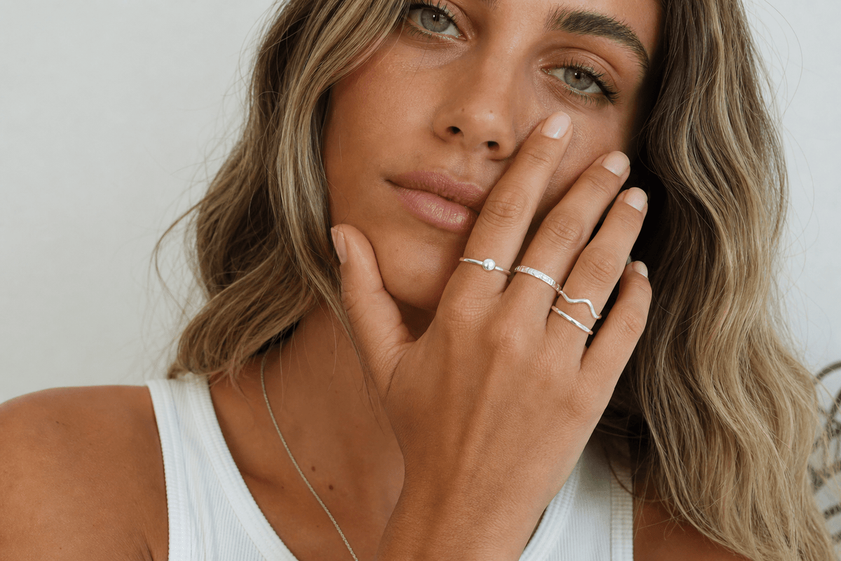 Young woman wearing multiple sterling silver rings on her hand in natural light
