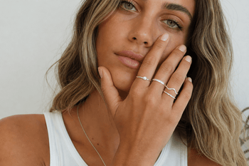Young woman wearing multiple sterling silver rings on her hand in natural light