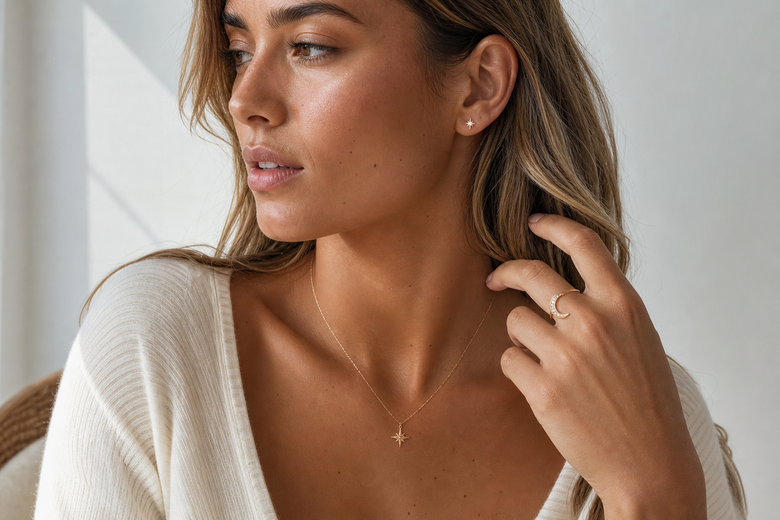 Young woman wearing delicate celestial jewellery including a star necklace, moon ring, and small earrings.