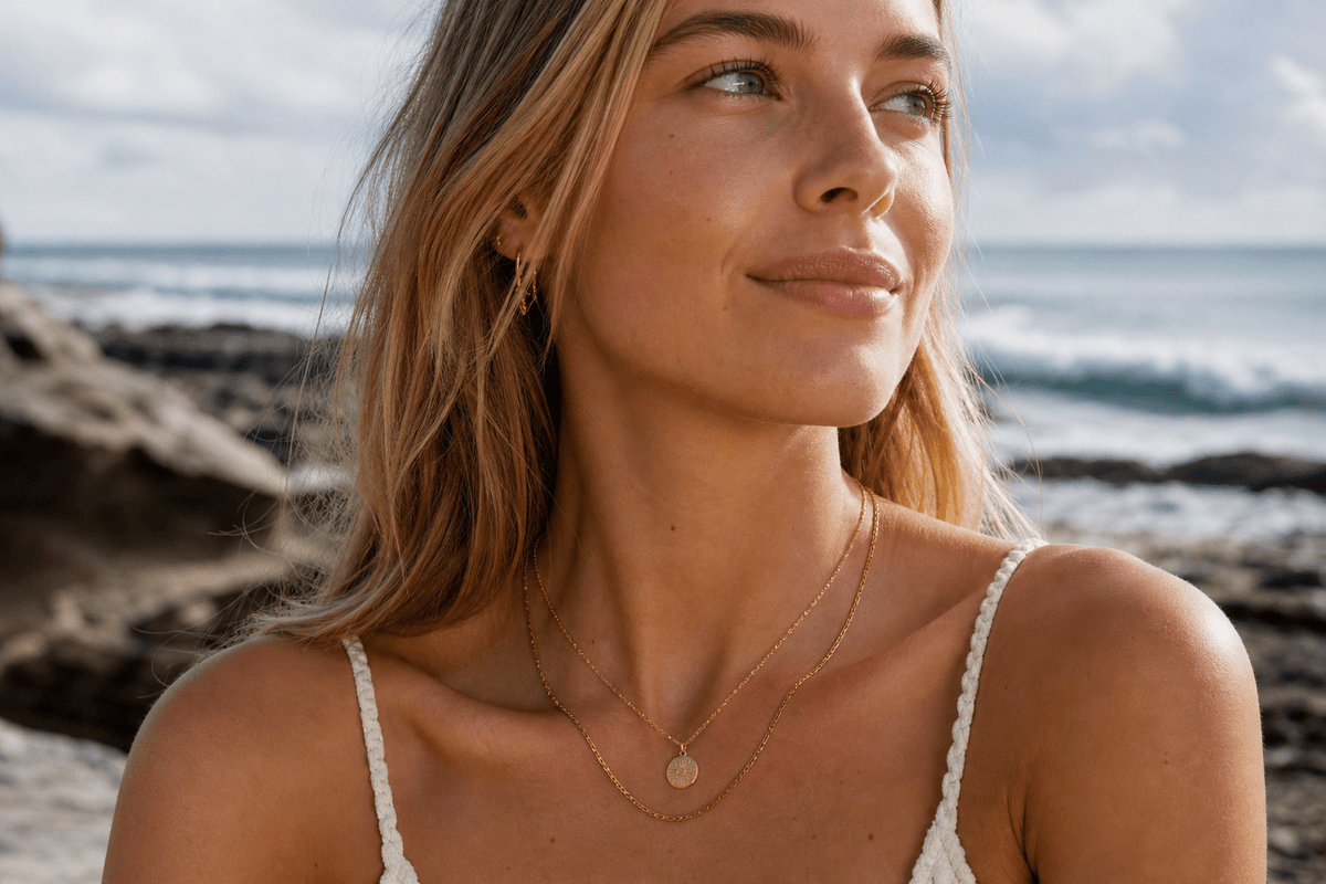 Young woman wearing two gold waterproof necklaces in natural light