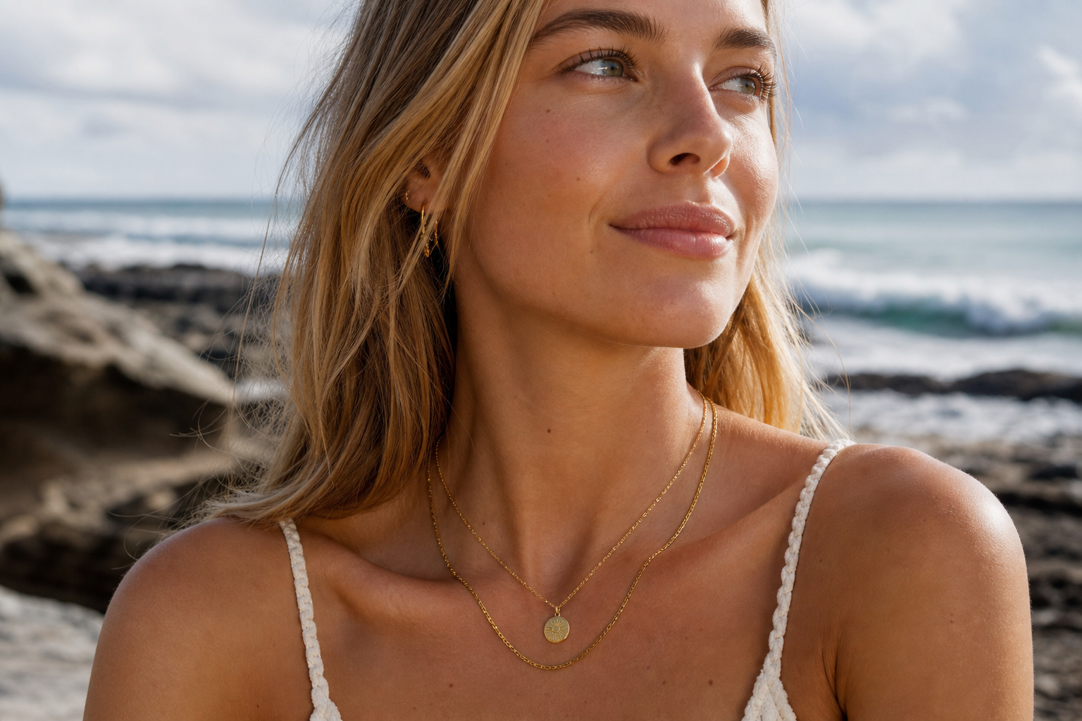 Young woman wearing two gold waterproof necklaces in natural light