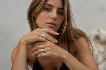 Young woman wearing several sterling silver rings on her hands in natural light