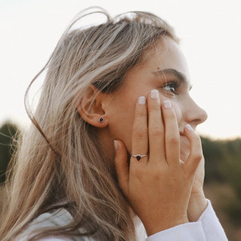 woman wearing birthstone stud earrings and ring