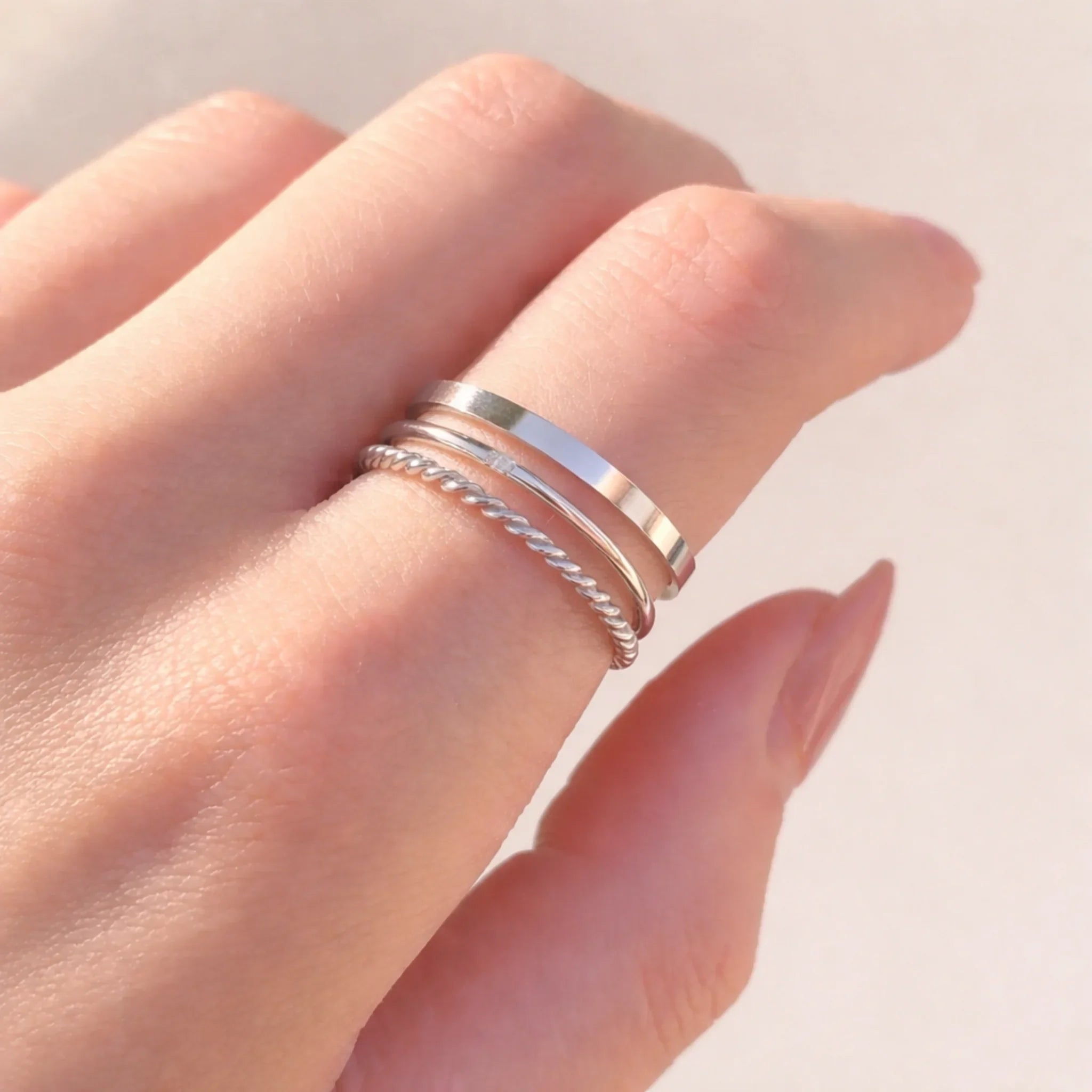 finger wearing three silver stacker rings