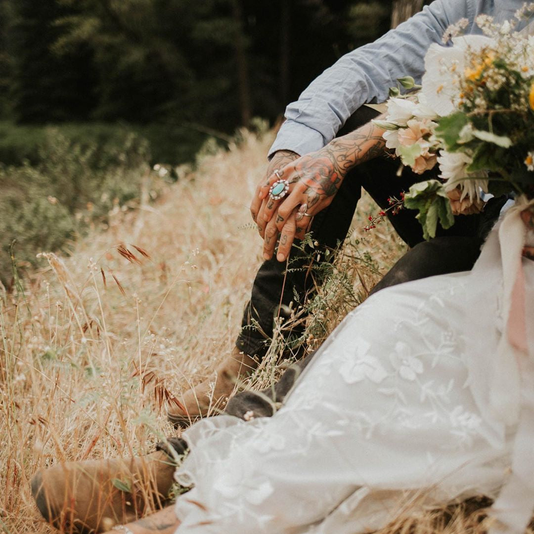 Person in a white dress holding a bouquet of flowers in a natural setting with a deer.