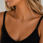 Close-up of a person wearing a delicate 18 inch cable chain sterling silver necklace against a neutral background