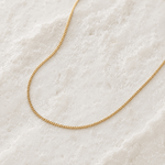 Gold chain necklace on a textured white surface