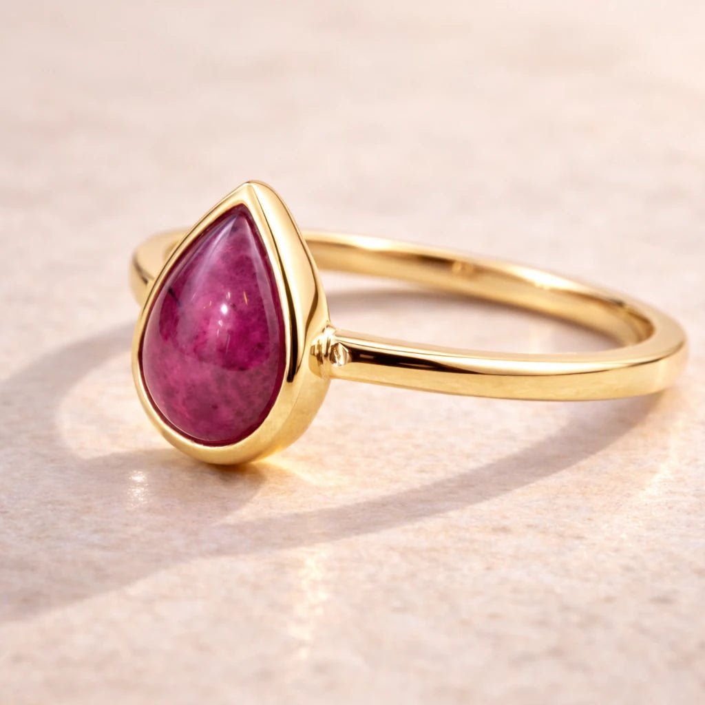 Gold ring with a natural ruby gemstone on a beige background