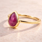 Gold ring with a natural ruby gemstone on a beige background