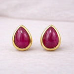 Gold-framed ruby teardrop earrings on a light background