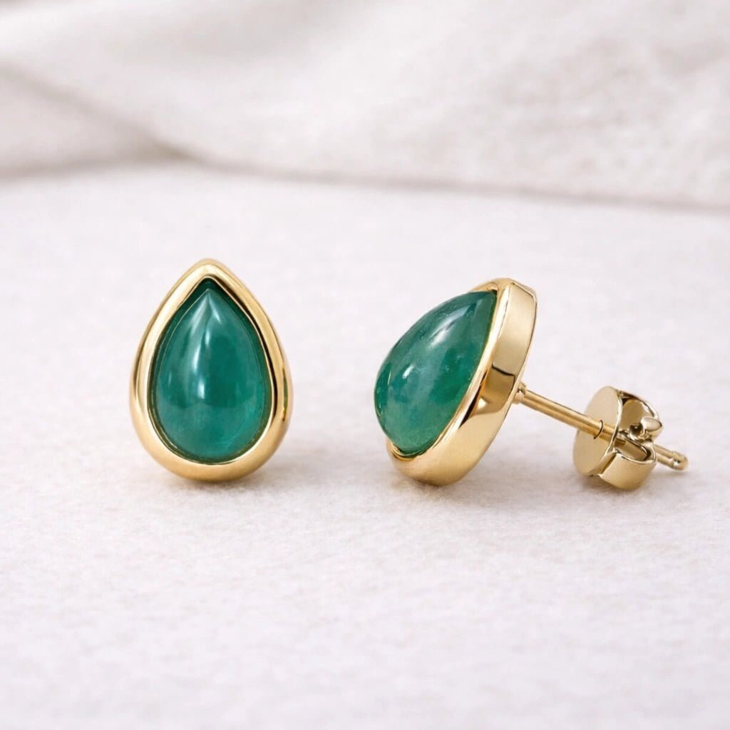 Gold stud earrings with green natural emerald gemstones on a white background