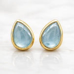 Gold-framed teardrop aquamarine stud earrings on a white background