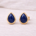 Pair of gold stud earrings with blue natural sapphire stones on a white background