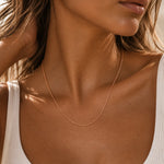 close up of a woman wearing a dainty minimalist 9k rose gold chain necklace with 1mm curb chain design and 18 inch length