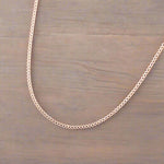 9k Rose Gold plated sterling silver curb chain necklace on a wooden surface