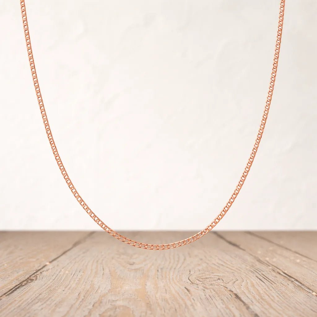 9k Rose gold plated sterling silver curb chain necklace on a wooden surface with a light background
