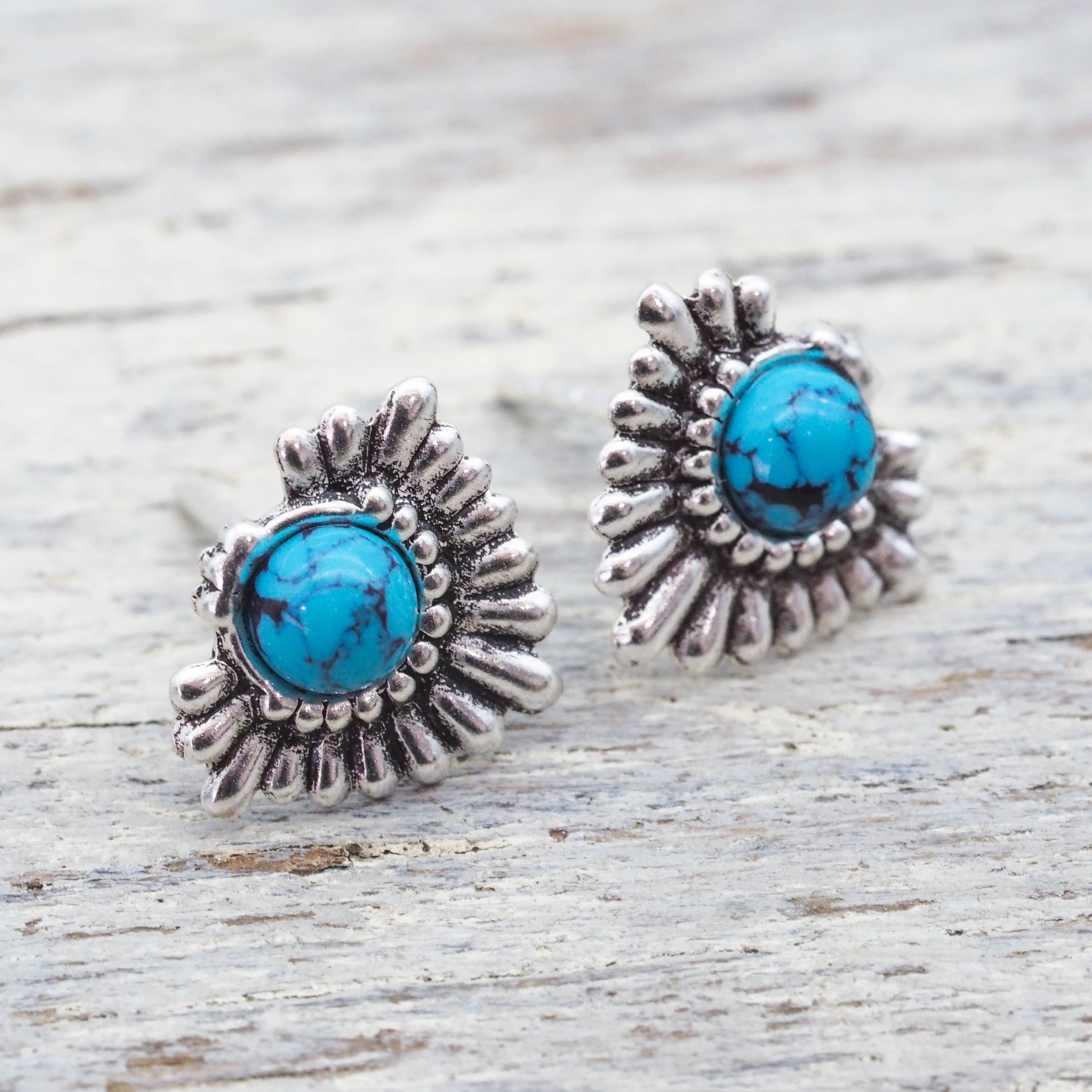 Silver earrings with turquoise stones on a wooden surface