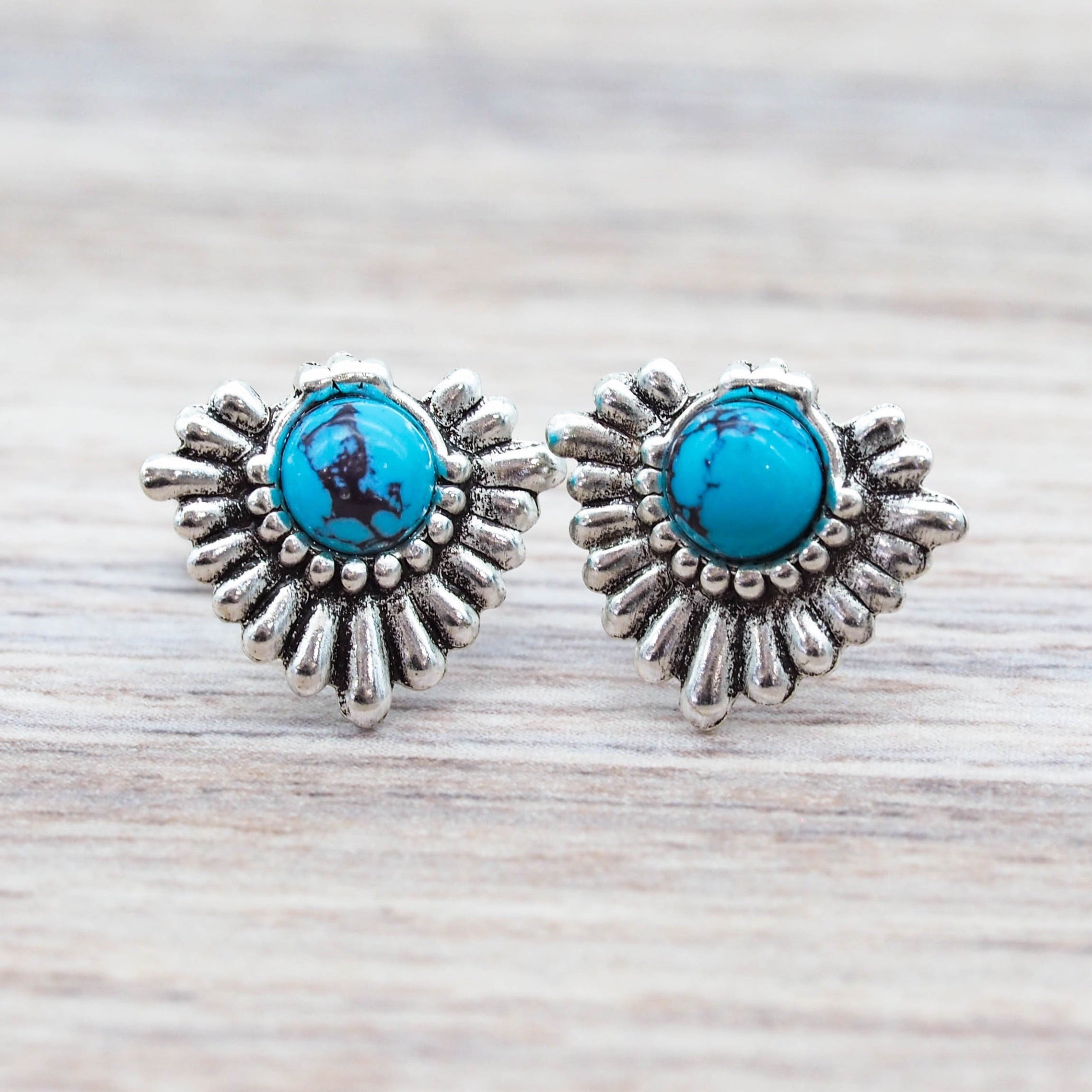 Silver earrings with turquoise stones on a wooden surface