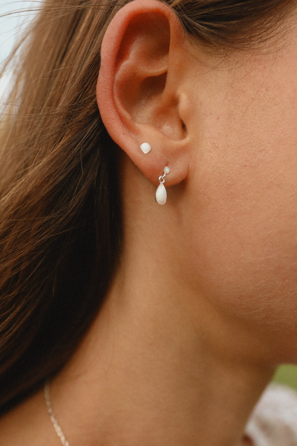 Close-up of an ear wearing a small earring with a blurred background