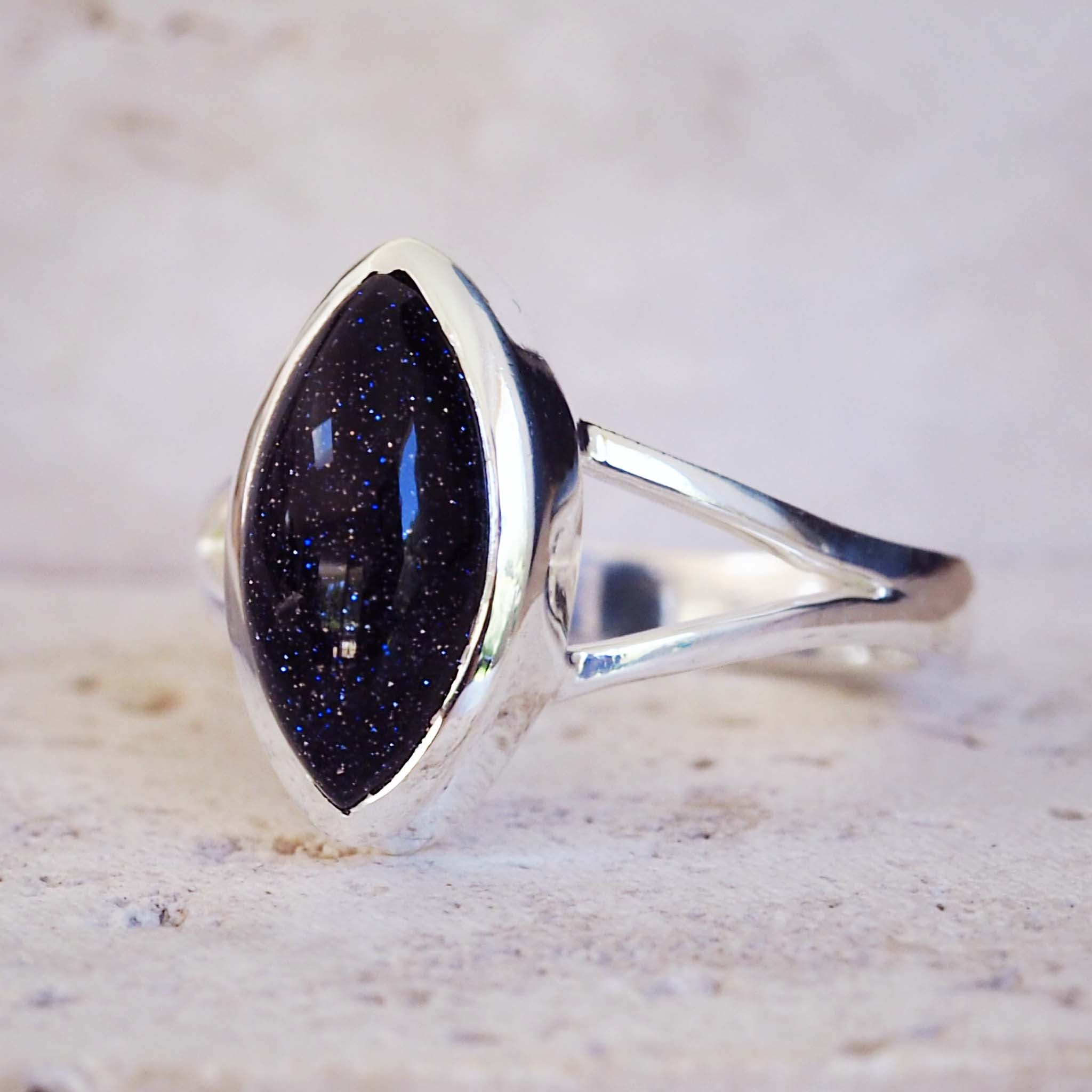Silver ring with a large black stone on a textured surface