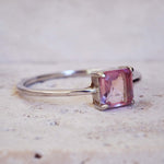 Silver ring with a pink gemstone on a light background