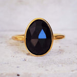 Gold ring with a black gemstone on a light background