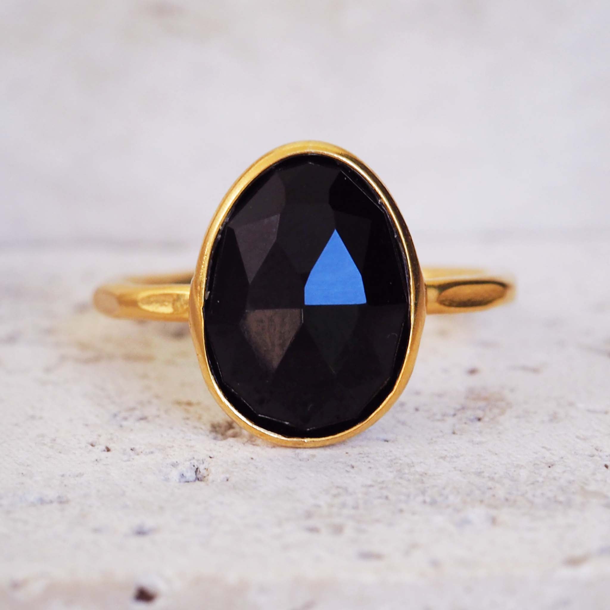 Gold ring with a black gemstone on a light background