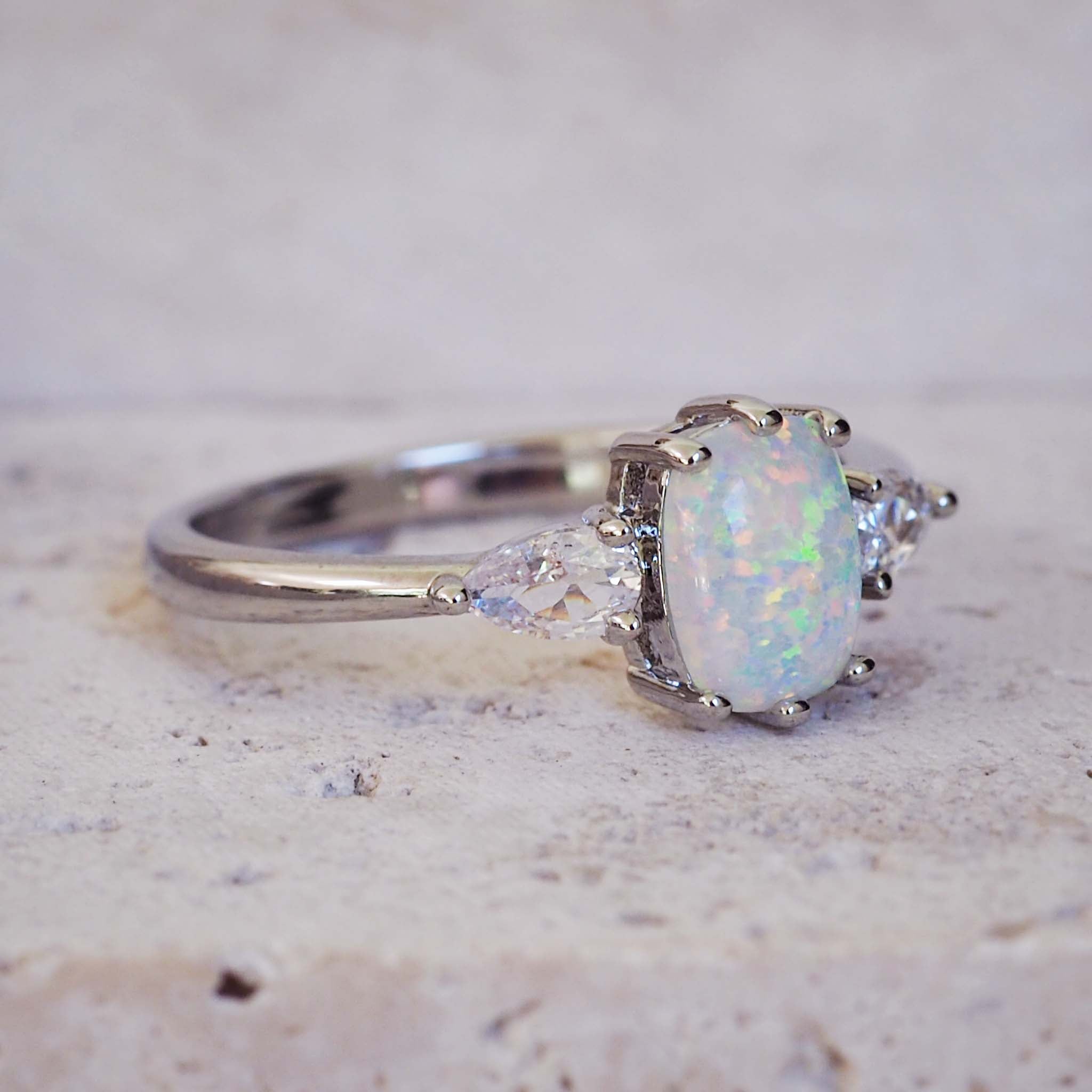 Silver ring with a central opal stone and smaller diamonds on a textured surface