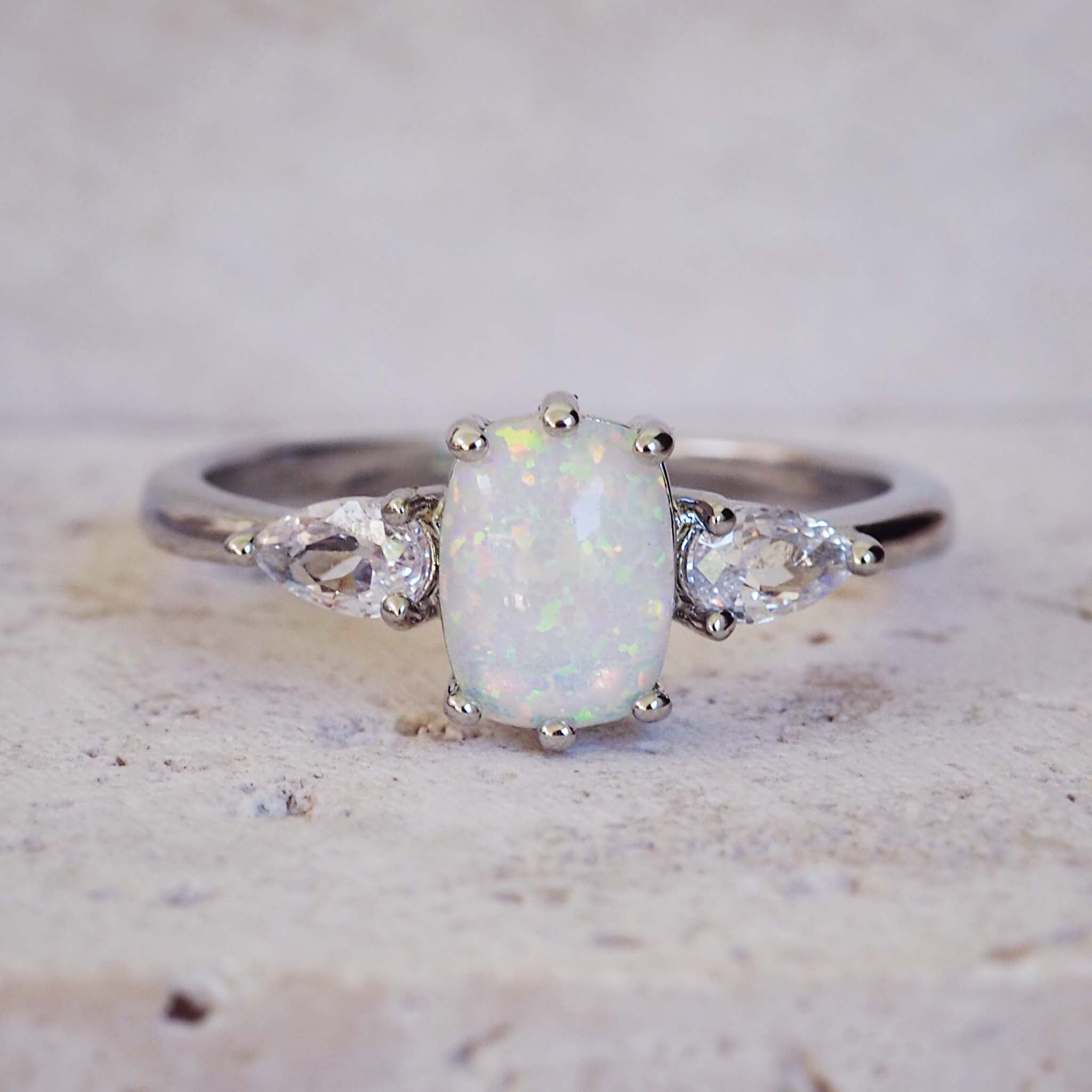 Silver ring with a central opal stone and smaller diamonds on a light background