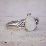 Opal ring with diamond accents on a textured surface