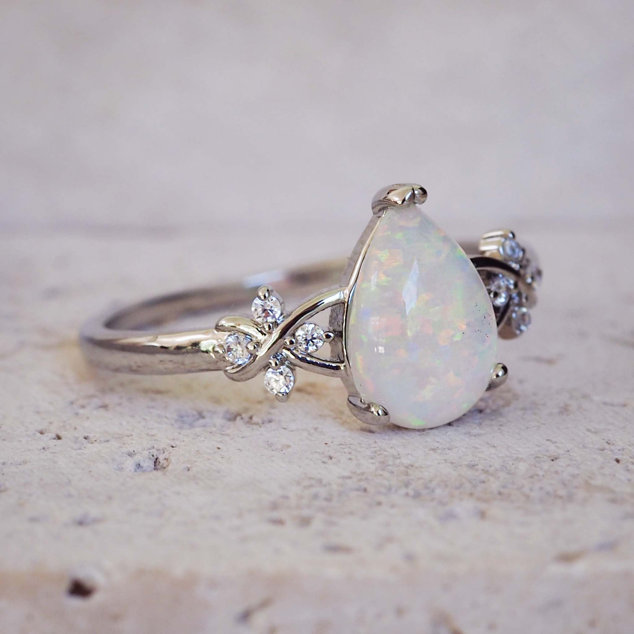 Opal ring with diamond accents on a textured surface