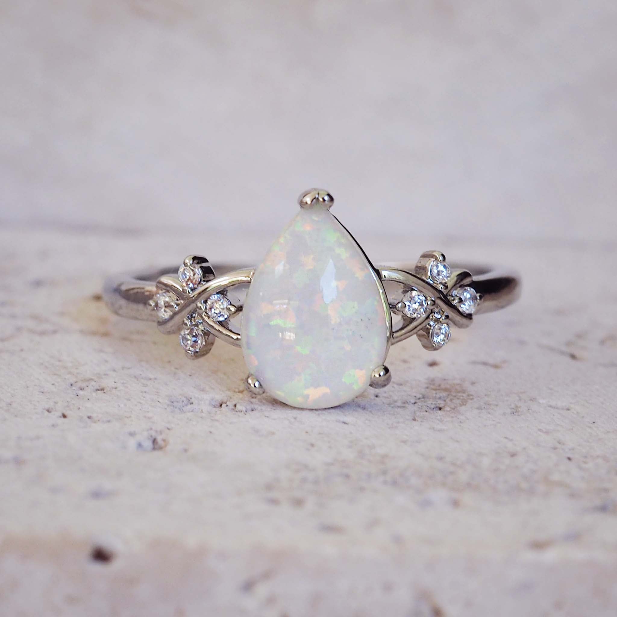 Opal ring with diamond accents on a textured surface