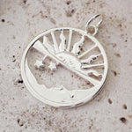 Silver pendant with tree design on a textured beige background