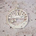 Silver pendant with sun and moon design on a textured surface