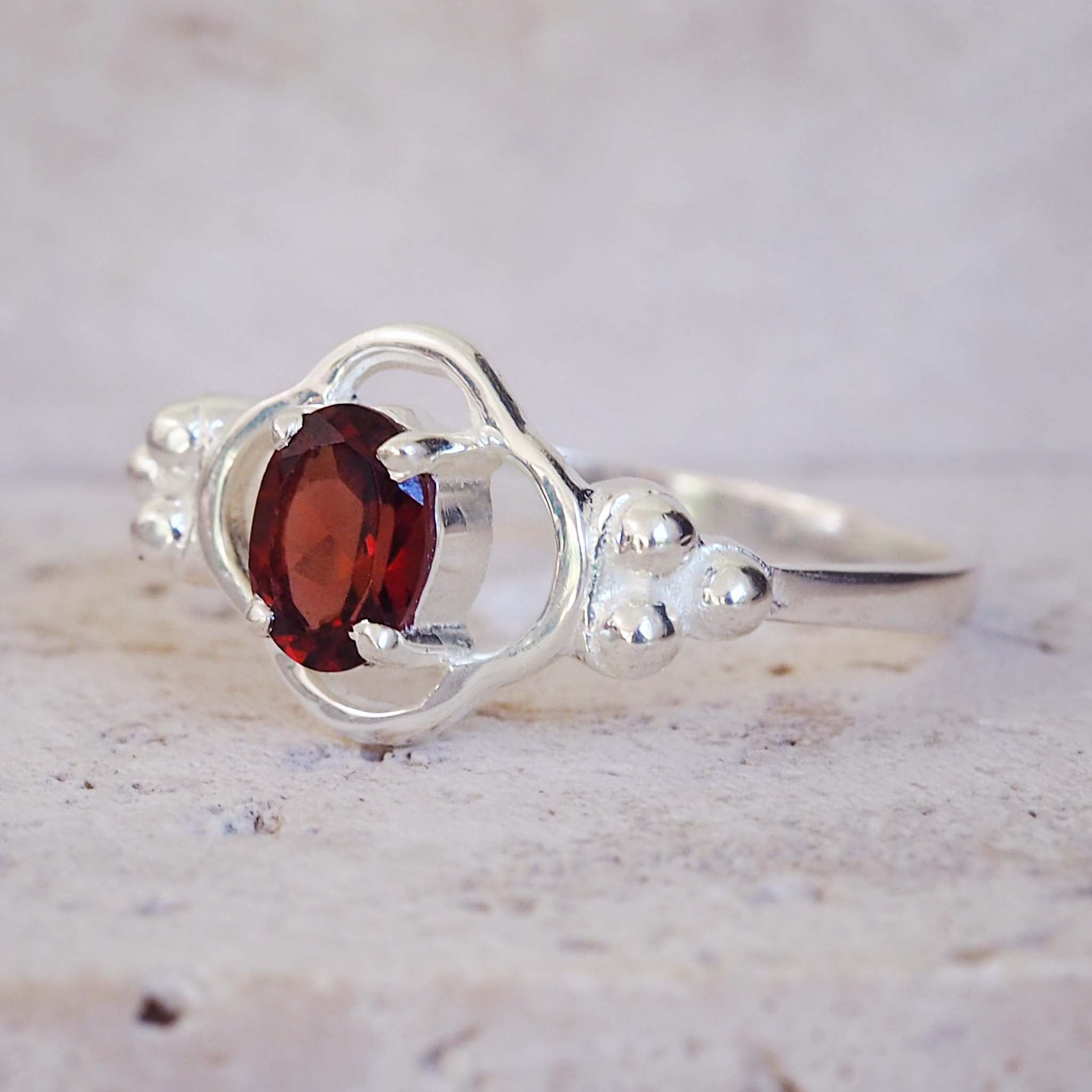 Silver ring with a red gemstone on a light background