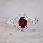 Silver ring with a red gemstone on a textured surface