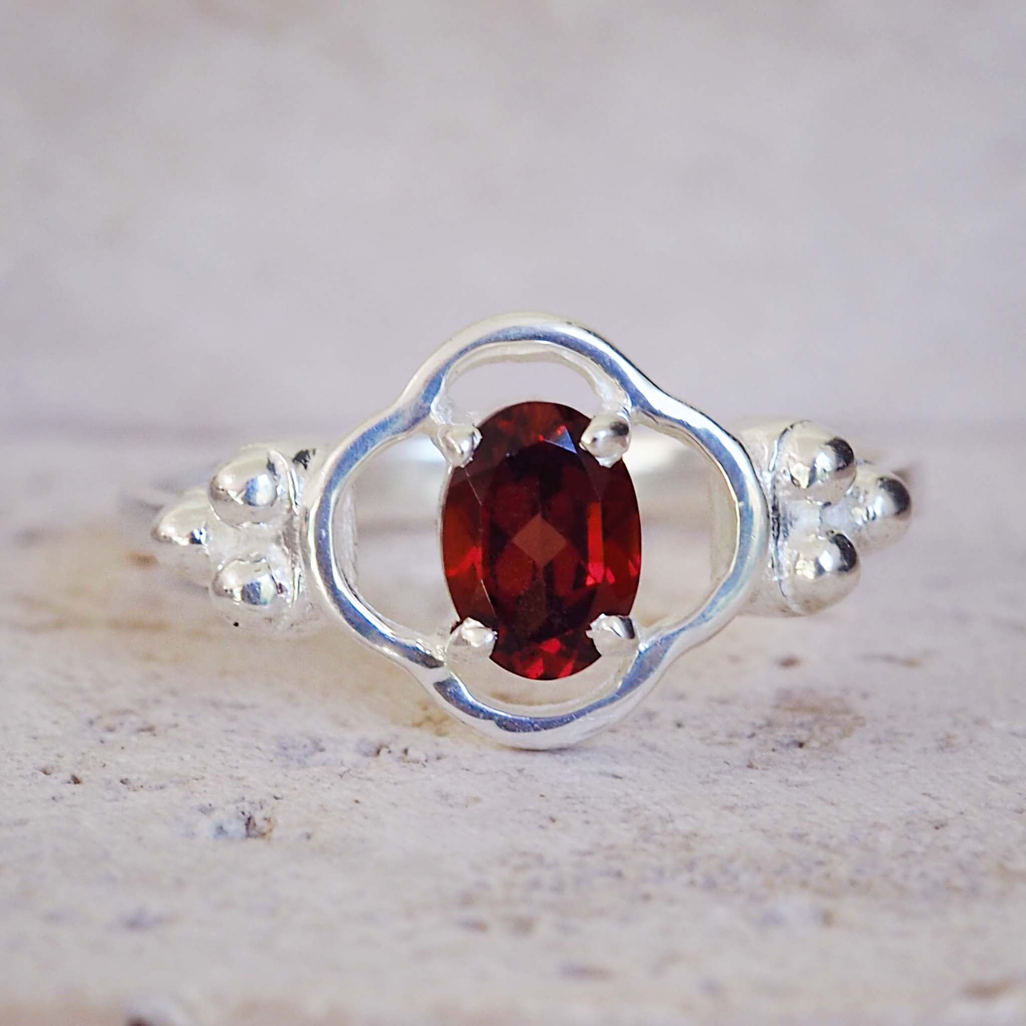 Silver ring with a red gemstone on a textured surface