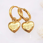 Gold heart-shaped earrings with eye design on a light background