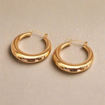 Gold hoop earrings on a beige background