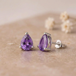 Amethyst stud earrings side view showing the sterling silver claw setting and butterfly back on beige stone