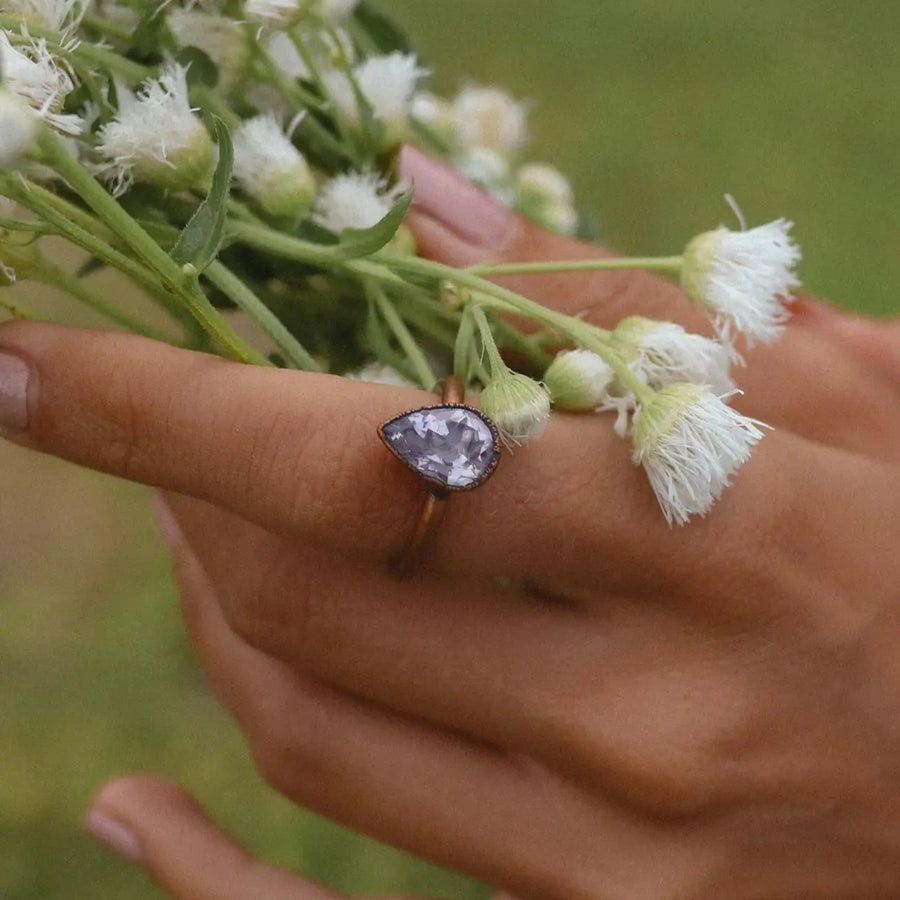 woman in a blue dress holding daisies wearing a copper ring with a purple teardrop shaped amethyst