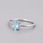 Sterling silver blue topaz ring with a faceted oval pale blue topaz, angled view