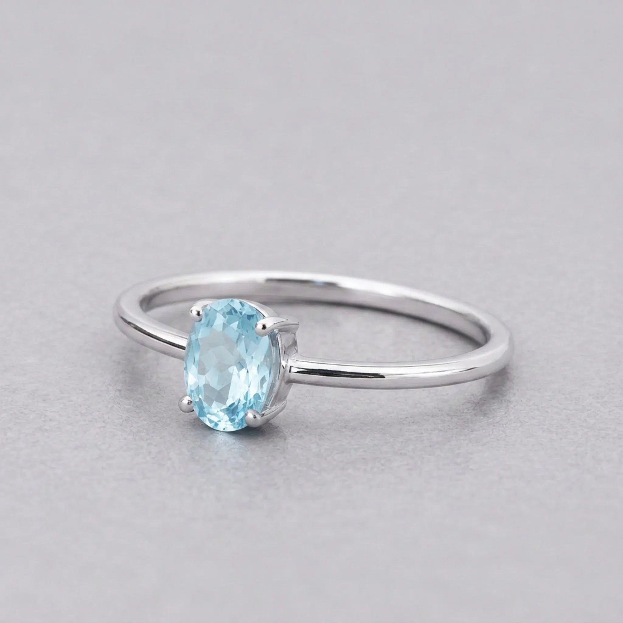 Sterling silver blue topaz ring with a faceted oval pale blue topaz, angled view