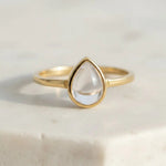 Gold April birthstone ring with clear herkimer quartz teardrop-shaped stone on a light background - quartz ring for gifting